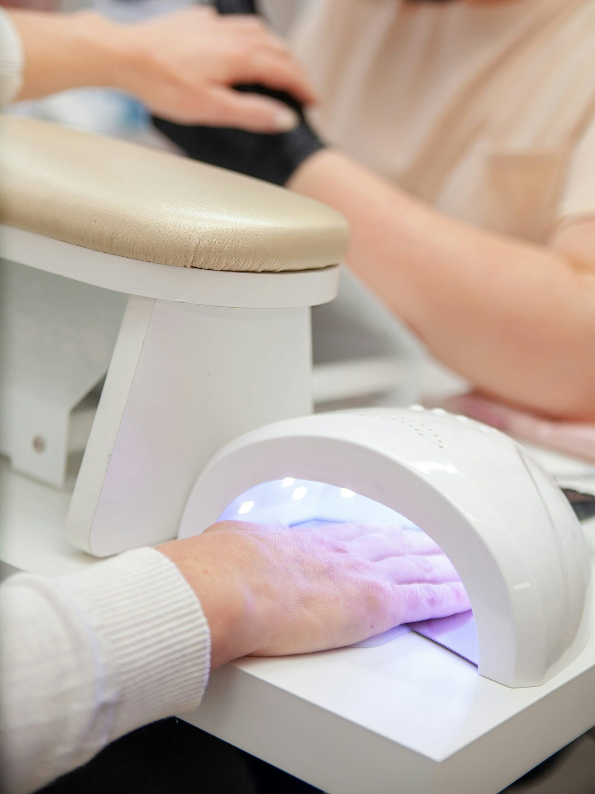 Kundin im Nagelstudio härtet ihre BIAB-Maniküre unter einer UV-Lampe aus