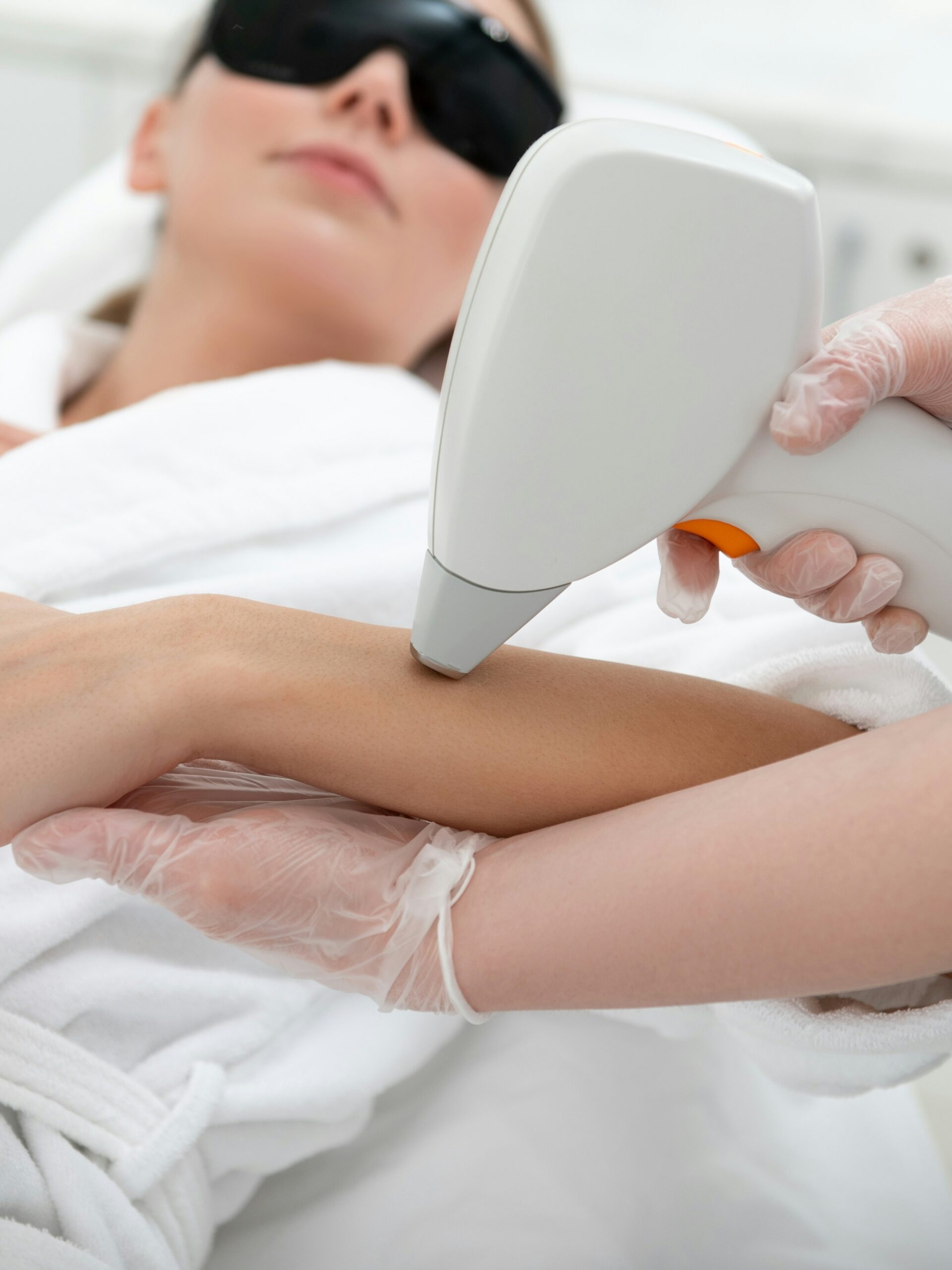Frau während einer IPL-Behandlung am Arm in einem Kosmetikstudio