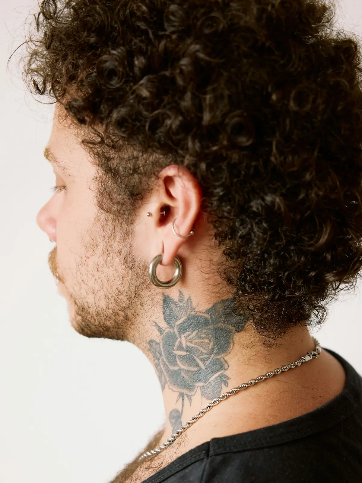 Aufnahme von hinten: ein Mann mit Ohrläppchen-, Helix- und Tragus-Piercings