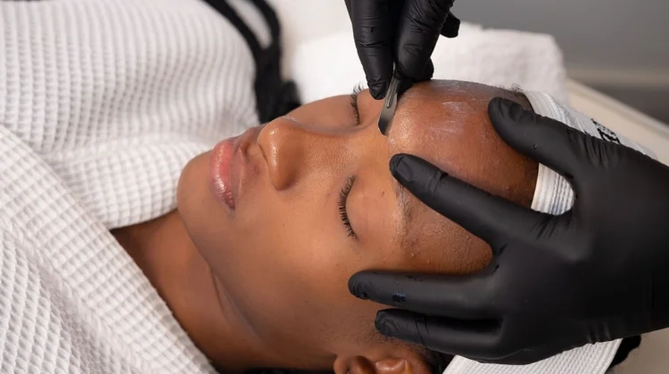 Nahaufnahme einer Kosmetikerin, die bei einer Kundin im Salon ein Dermaplaning durchführt