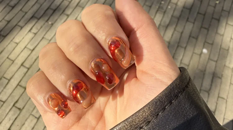 Lava-Nail-Art mit bernsteinfarbenen und roten Wirbeln auf transparenter Basis