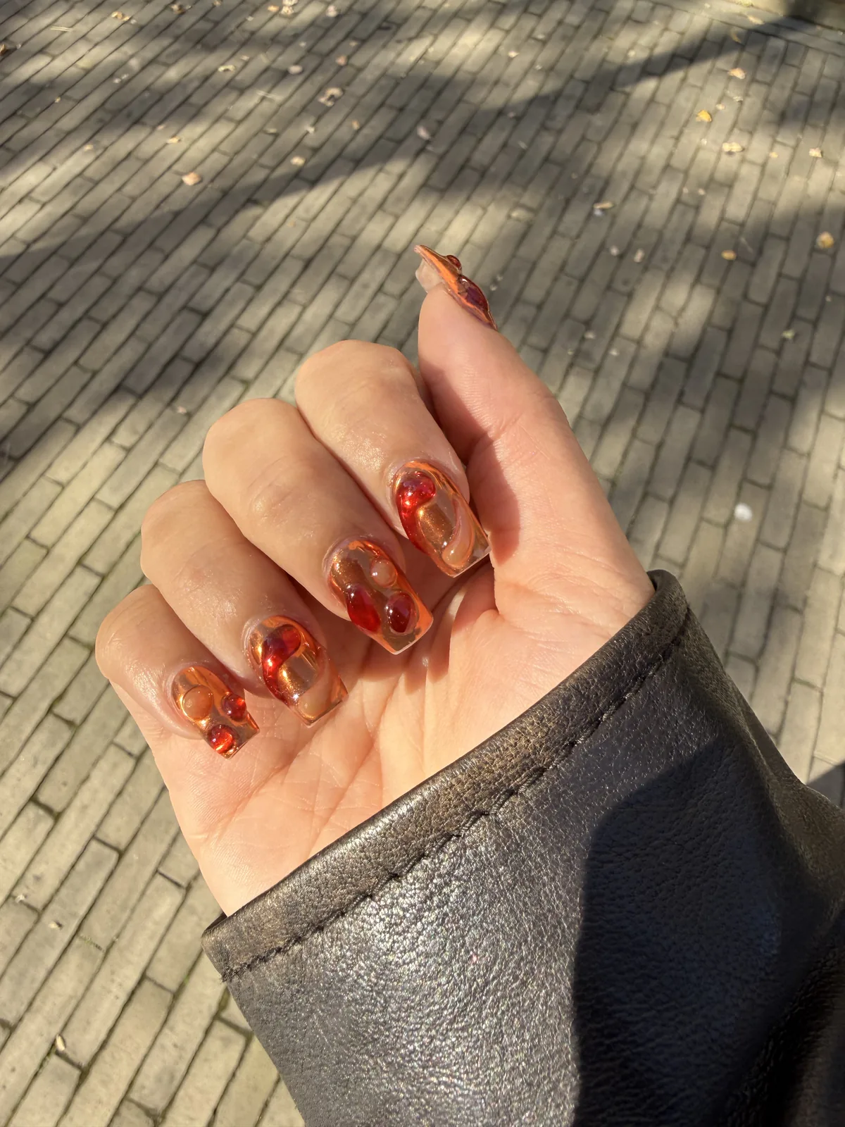 Lava-Nail-Art mit bernsteinfarbenen und roten Wirbeln auf transparenter Basis
